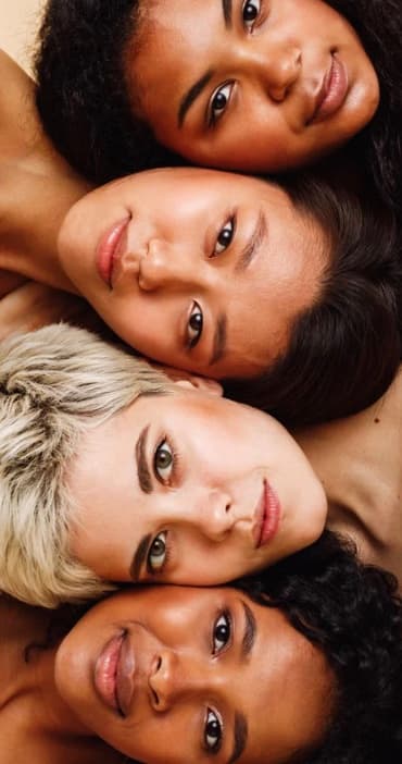 Quatre femmes aux carnations différentes, tête contre tête, en lumière naturelle